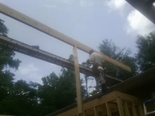Carpenter setting a ridge beam over a new addition frame — Ice Dam Removal by Roofing Brothers in Troy