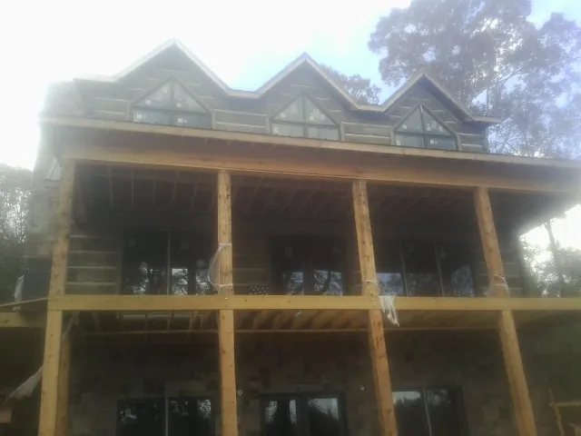 Dormers and porch framing on a large log home under construction — Roof Coating work by our crew in Troy