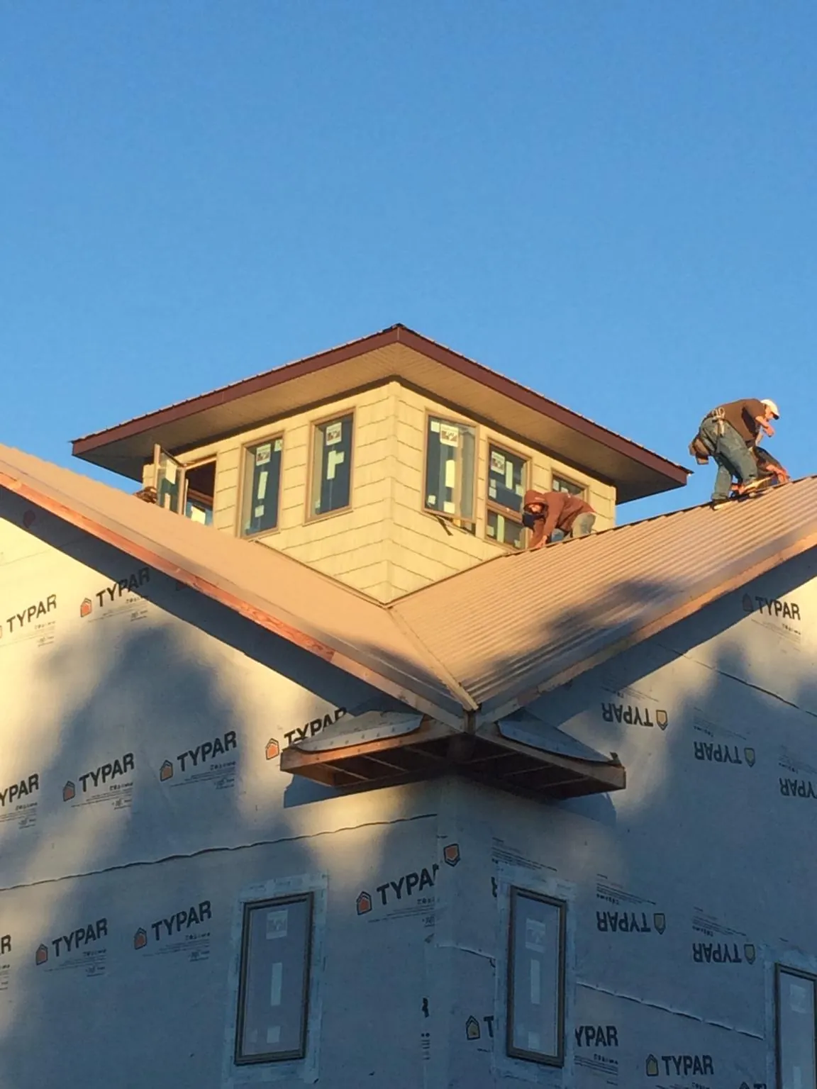 Roofers working around a rooftop cupola on a new metal roof at sunset — Roof Waterproofing in Troy by Roofing Brothers